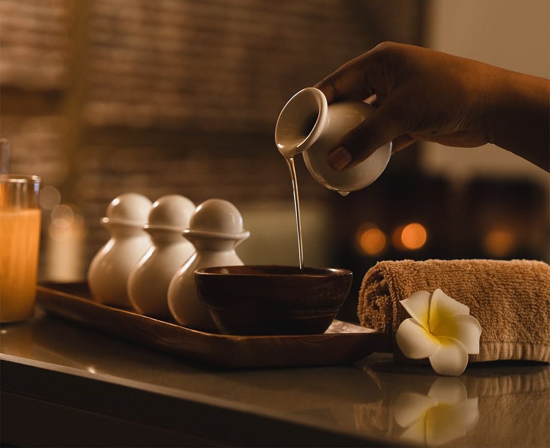 Warm oil being poured into a wooden bowl